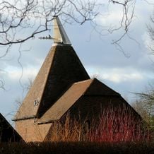 Impression der Schneeglöckchenreise Galanthour von Iris Ney - DIE Gartenreise in den Vor-Frühling nach England. Hinter den roten und orangefarbenen Flammen rindenfärbender Hartriegel erhebt sich ein für die Region Kent typischer Brauerei-Turm.