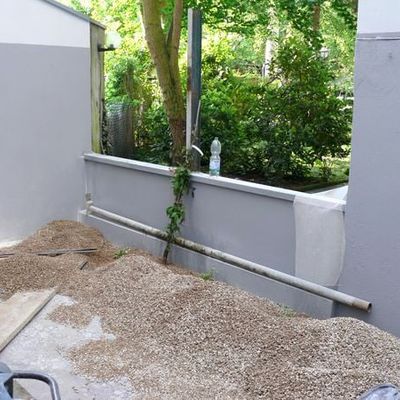 Nach Abrütteln des aufgestämmten Betonbodens wird dieser als Unterbau für eine Schicht aus Kalksplitt 5-11 mm verwendet. Um ein Hochdrücken des Unterbaus in die Kiesschicht zu verhindern, wurde vorher grobmaschiges Trenngewebe aus Kunststoff eingebracht.